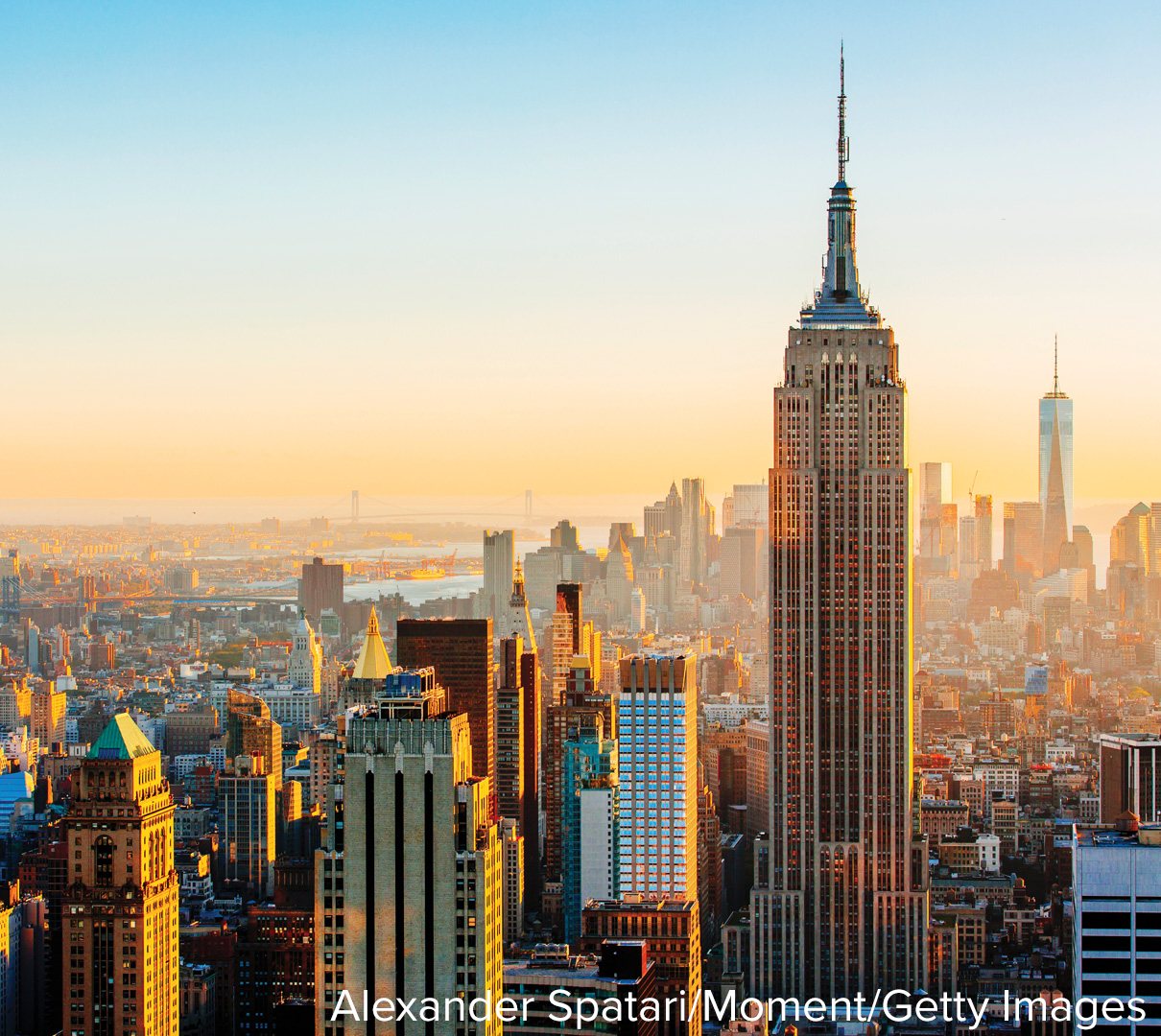 A city skyline at sunrise, dense with skyscrapers stretching to the horizon.