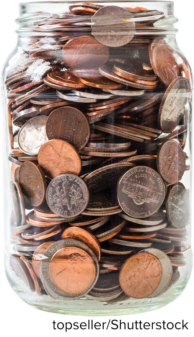 A glass jar packed full of mixed coins — pennies, nickels, dimes and quarters.